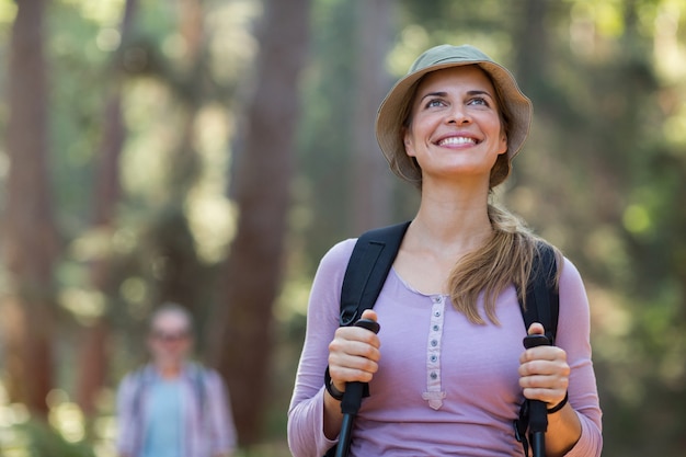 Glimlachende vrouwenwandelaar die met trekkingspolen wandelen