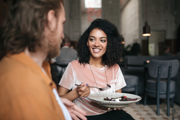 Glimlachende vrouwenzitting in restaurant met vriend