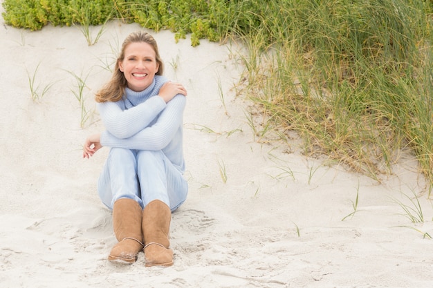 Glimlachende vrouwenzitting op het zand