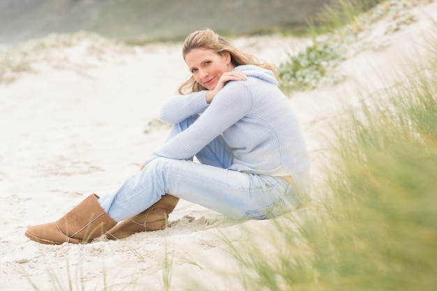 Glimlachende vrouwenzitting op het zand