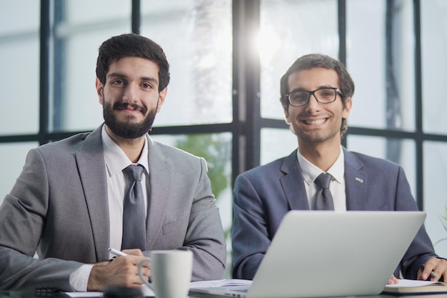 Glimlachende zakenlieden met computer in modern kantoor