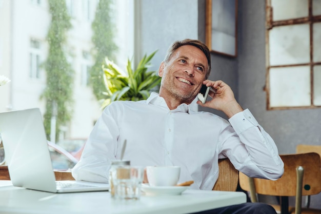 Glimlachende zakenman aan de telefoon in café