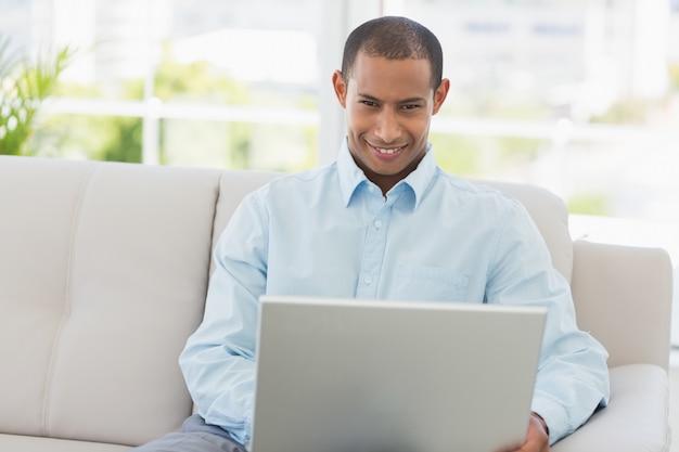 Glimlachende zakenman die aan laptop op de laag werkt