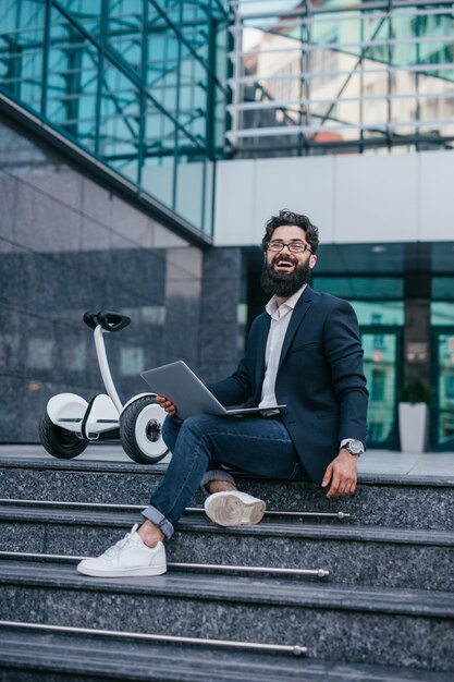 Glimlachende zakenman die aan marmeren treden met laptop werkt