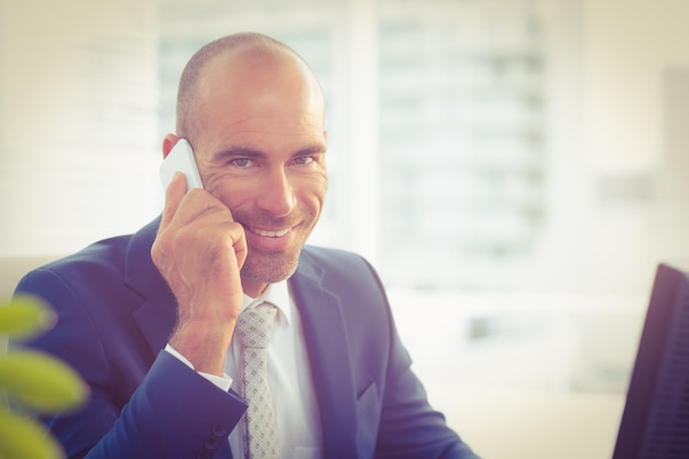 Glimlachende zakenman die de telefoon uitnodigt