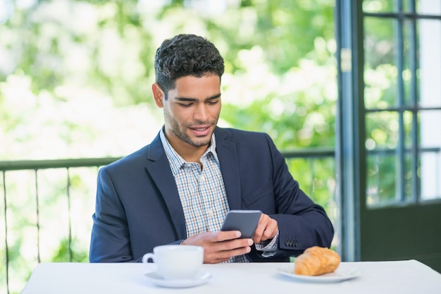 Glimlachende zakenman die mobiele telefoon met behulp van