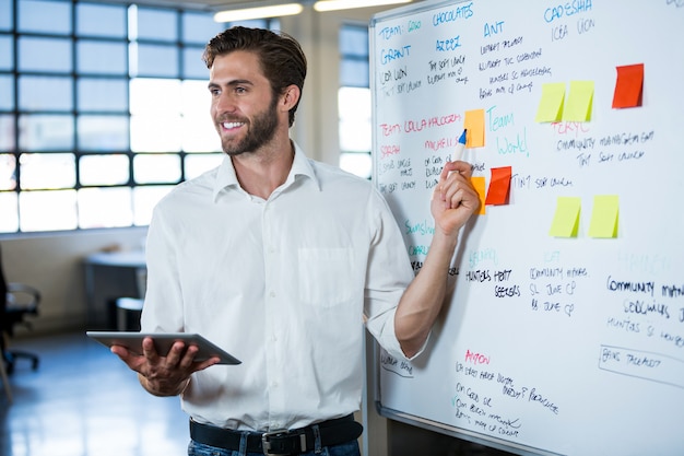 Glimlachende zakenman die op whiteboard richt