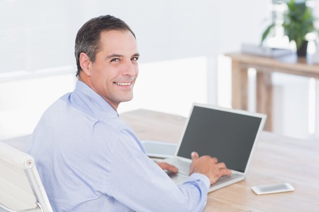 Glimlachende zakenman die zijn computer met behulp van