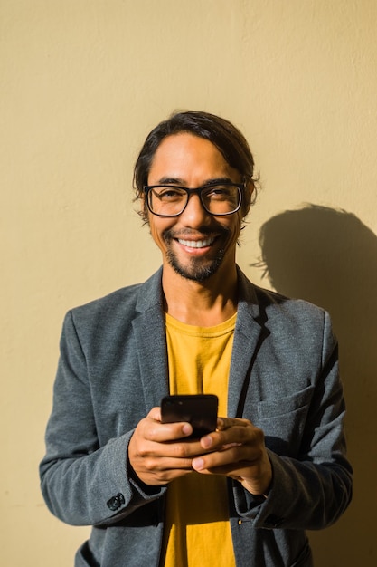 Glimlachende zakenman die zijn mobiele telefoon vol vertrouwen vasthoudt