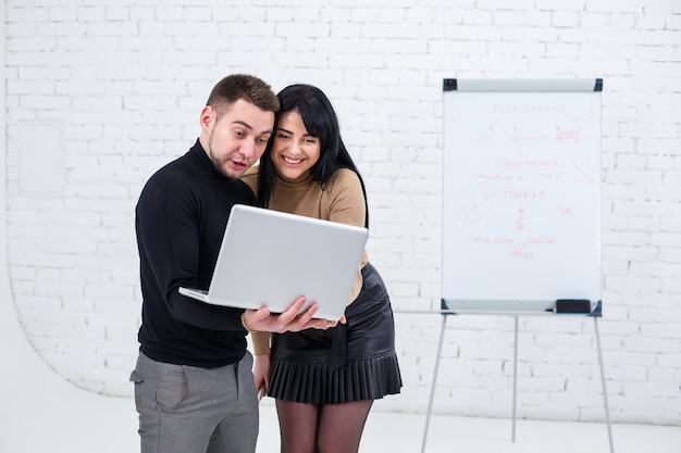 Glimlachende zakenman en vrouwelijke manager staan met laptop en kijken naar het scherm. Staan op een witte achtergrond.