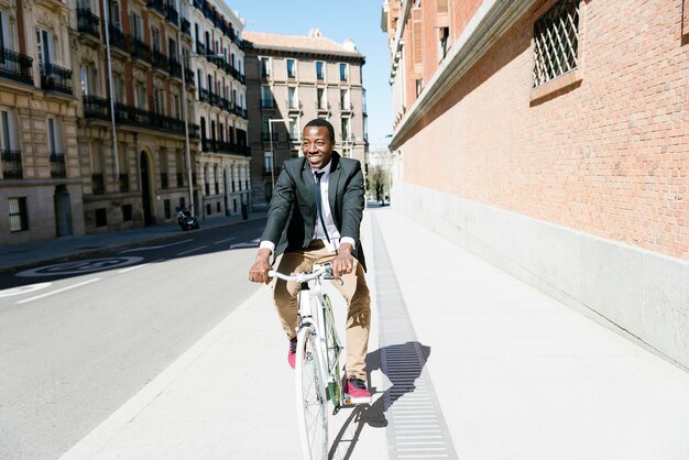 Foto glimlachende zakenman fietsen op fiets in de stad