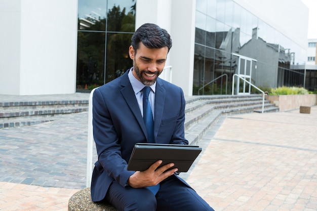 Glimlachende zakenman met behulp van digitale tablet in het kantoorpand