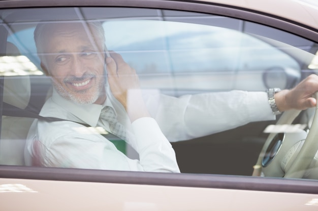 Glimlachende zakenman op de telefoon in zijn auto
