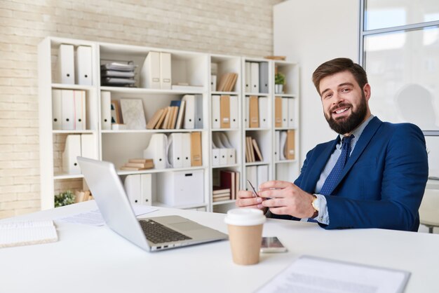 Glimlachende Zakenman Posing At Desk in Bureau