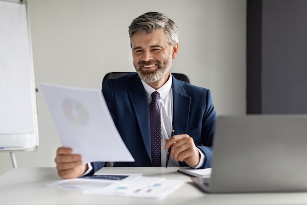Foto glimlachende zakenman van middelbare leeftijd werken met papieren aan balie in office
