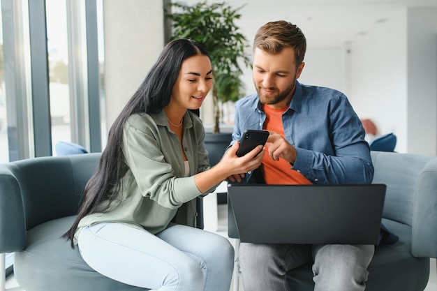 Glimlachende zakenmensen werken samen aan computer brainstorm over opstarten van bedrijf tijdens kantoorvergadering Gemotiveerde diverse collega's kijken naar laptopscherm bespreken samen zakelijke projectideeën