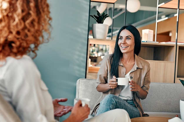 Glimlachende zakenvrouw in gesprek met zakenpartner in café Aantrekkelijke vrouwelijke vrienden die koffie drinken in coffeeshop