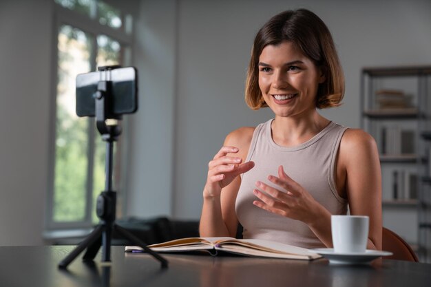 Glimlachende zakenvrouw in vrijetijdskleding die videoblog maakt met smartphone