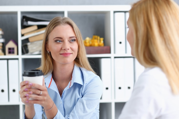 Glimlachende zakenvrouw koffie drinken uit een papieren beker