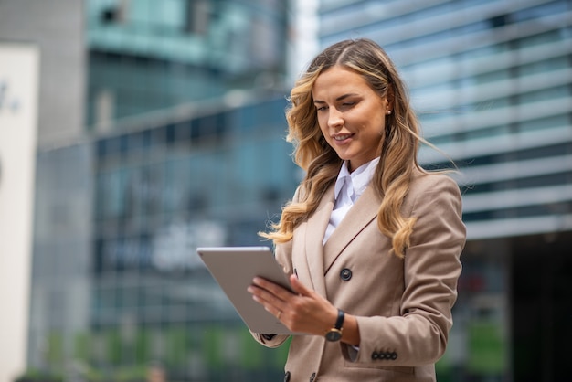 Glimlachende zakenvrouw met behulp van een digitale tablet buiten