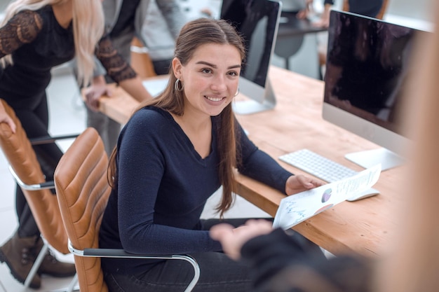 Glimlachende zakenvrouw praat terwijl ze aan een bureau zit