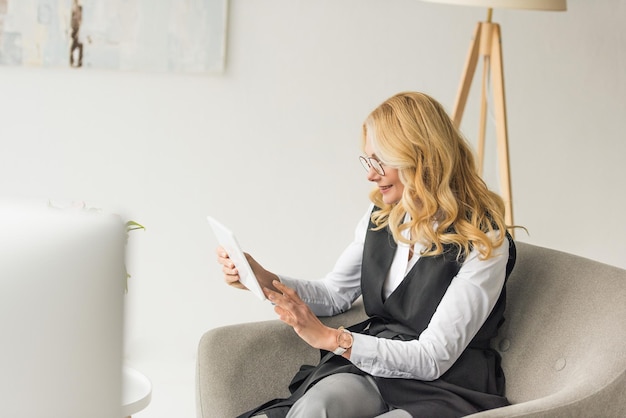 glimlachende zakenvrouw van middelbare leeftijd in een bril met een digitale tablet