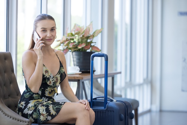 Glimlachende, zelfverzekerde, moderne vrouw praten via de telefoon in de lobby van het hotel