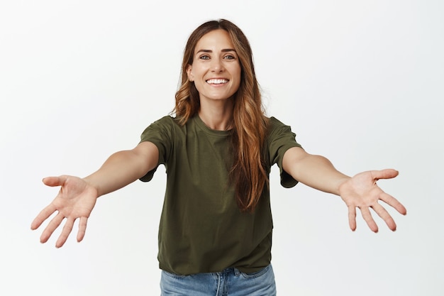 Glimlachende zorgzame volwassen vrouw, moeder spreidde handen zijwaarts om te knuffelen