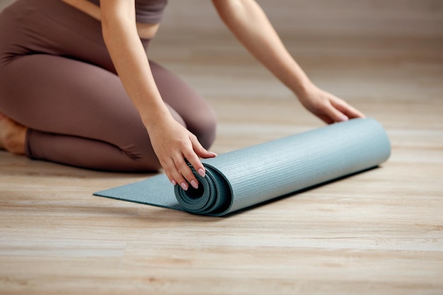 Glimlachende zwangere vrouw in sportkleding klaar voor ochtendgymnastiek of oefening Gelukkige jonge vrouw volgt een gezonde levensstijl tijdens de zwangerschap, houdt yogamat vast voor Pilates of stretching