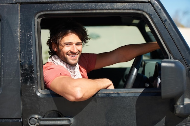 Foto glimlachportret en man in een busje op weg met vrijheid reizen en woestijn avontuur voor zomervakantie vervoer vakantie reis en gelukkige chauffeur in de auto met natuur zonneschijn en het platteland