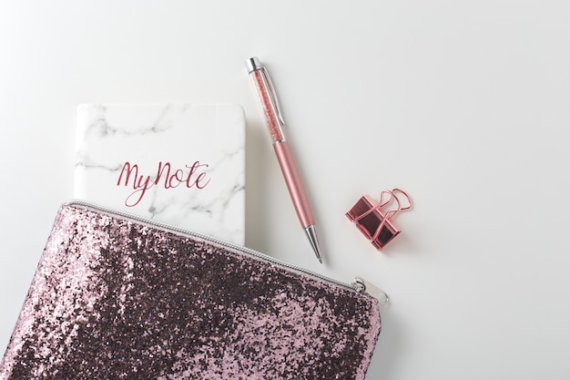 Glitter bag with pen and planner on white desk