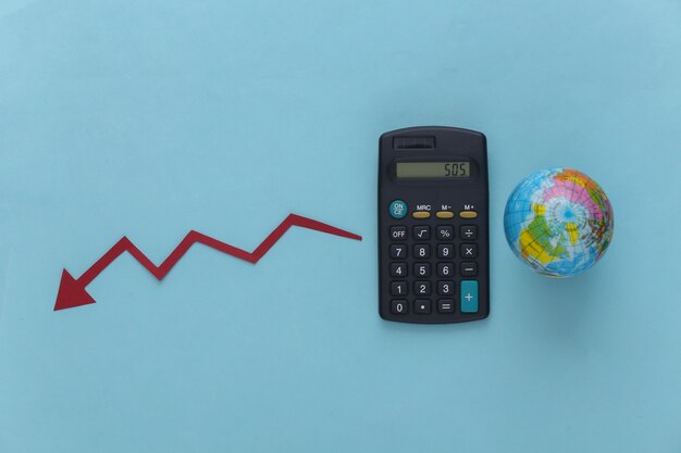 Тема глобального кризиса. Калькулятор с глобусом, падающая стрелка, стремящаяся к синему