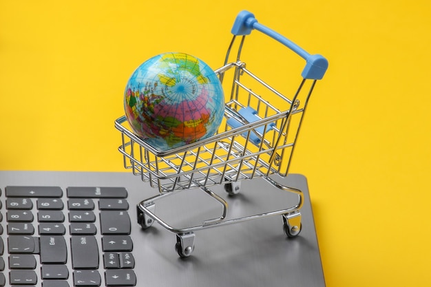 글로벌 온라인 슈퍼마켓. 노트북 키보드에 세계와 쇼핑 트롤리