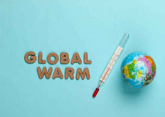 Global warming concept. Globe and thermometer on blue