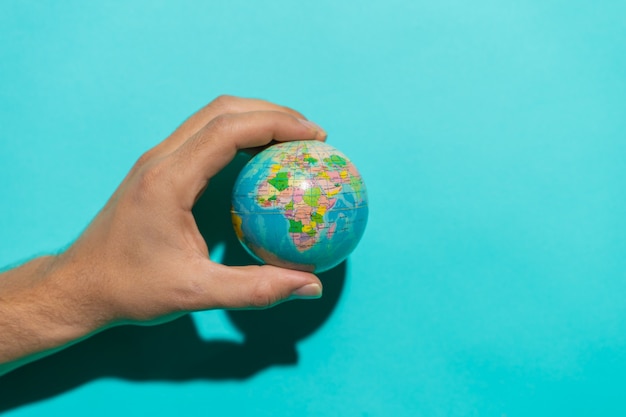 Globe ball in top of a red book in a stool with colorful blue background with copy space for text