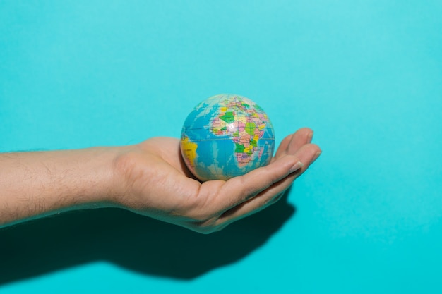 Globe ball in top of a red book in a stool with colorful blue background with copy space for text