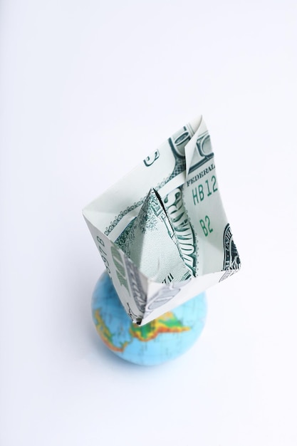 Globe and a paper boat out of a dollar bill