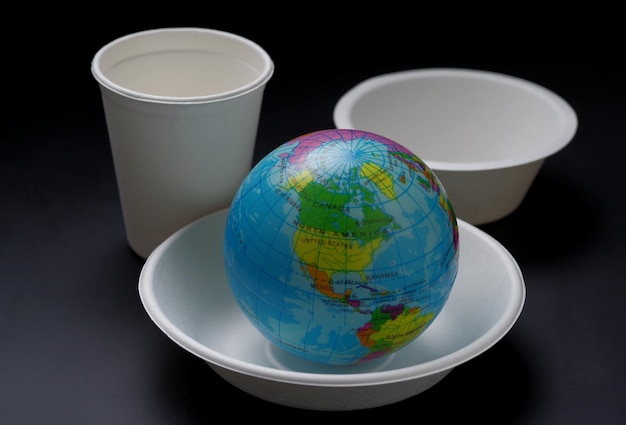 A globe sits on a plate next to a cup of water.