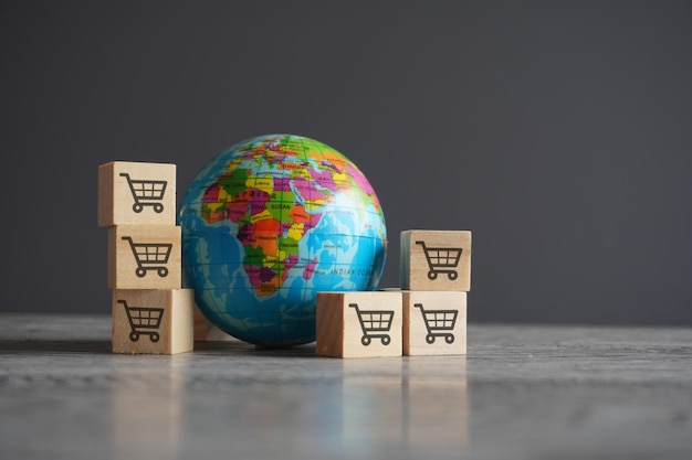 Globe and wooden cubes with shopping trolley icon Global retail international business concept