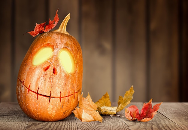 Gloeiende Halloween-pompoen Jackolantern en Herfstbladeren op houten pagina