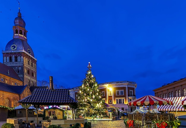 Gloeiende kerstboom en markt in de buurt van de kathedraal van Riga, gelegen aan het koepelplein in het oude Riga, Letland. Koepelkathedraal werd gebouwd in de buurt van de rivier de Daugava. Selectieve focus