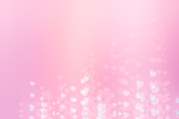 Foto gloeiende witte hartjes op een roze achtergrond met bokeh-effect