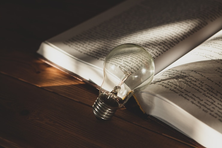 Foto gloeilamp en boek op tafel. nieuwe ideeën