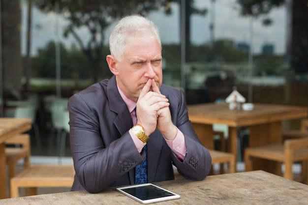 Gloomy Entrepreneur with Tablet in Street Cafe