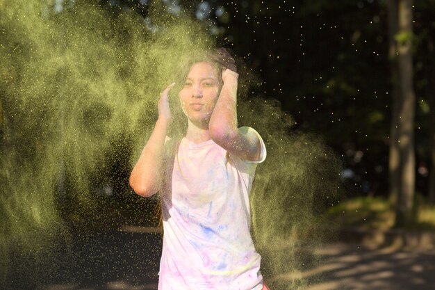 Glorious brunette asian woman with long hair playing with Holi paint exploding around her