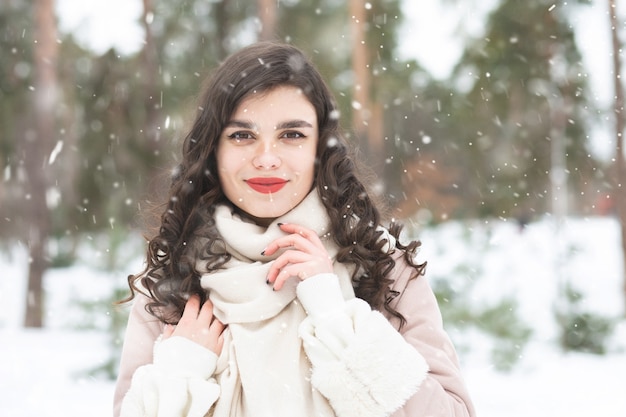 Glorious brunette woman with long hair wears coat in snowy weather. Space for text
