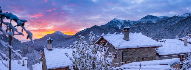 Glorious sunset in the italian Alps Beautiful sky over snowy valley idyllic village and snowcapped mountain peaks Winter in Piedmont Italy