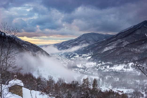 Glorioso tramonto nelle alpi italiane bel cielo sulla valle innevata villaggio idilliaco e cime innevate inverno in piemonte italia