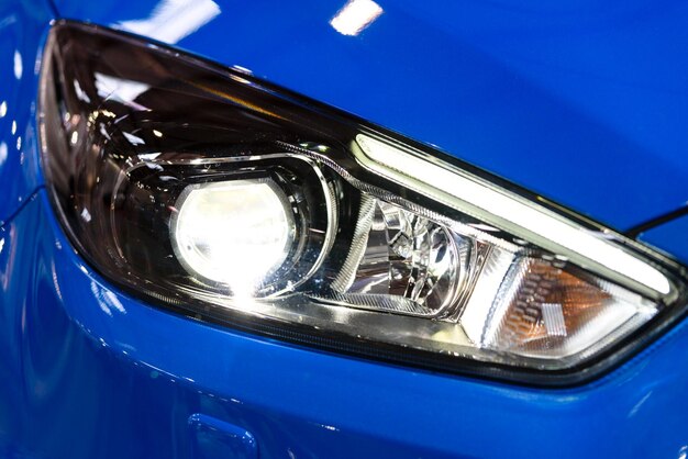 Glossy headlamp in a modern blue car in closeup