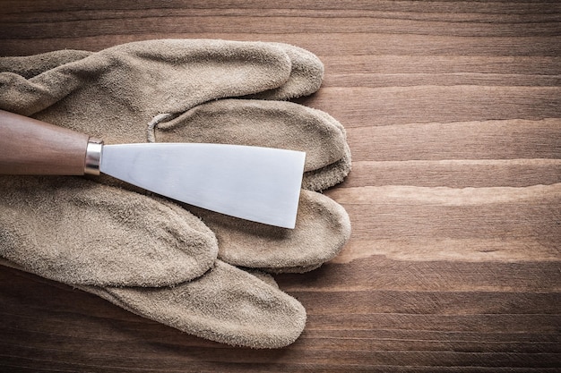 Glove and paint scraper on wooden board